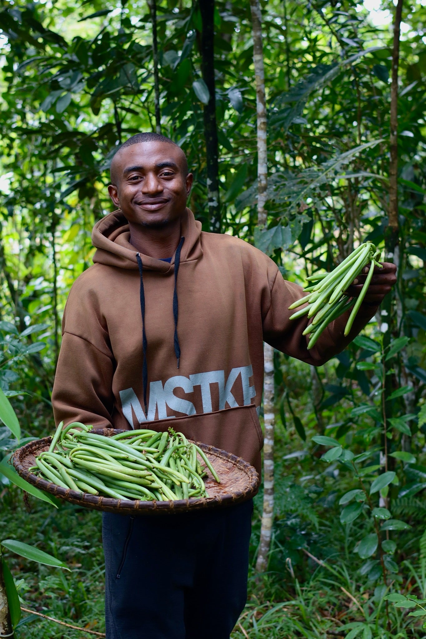 Jeune producteur de vanille avec un plateau de gousses